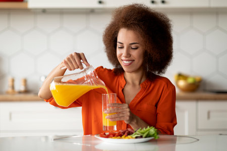 Portrait of smiling black woman having healthy breakfast in kitchen at homeの写真素材
