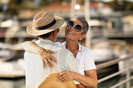 Loving Mature Couple Hugging At Marina Port With Sailboats Outsideの写真素材