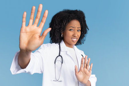 Sad dissatisfied millennial african american lady in white coat with stethoscope do stop gesture