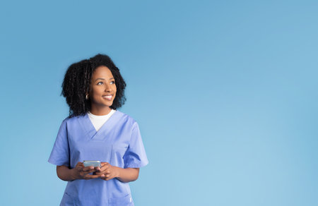 Cheerful millennial african american lady in uniform chatting on smartphone, look at free space