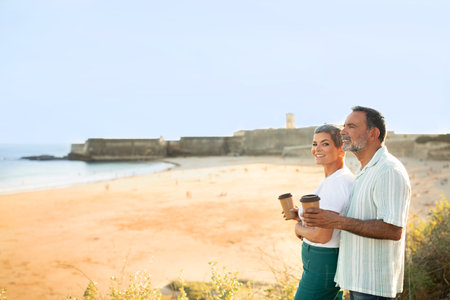 Happy Senior Couple With Coffee Cups Posing At Ocean Outdoor