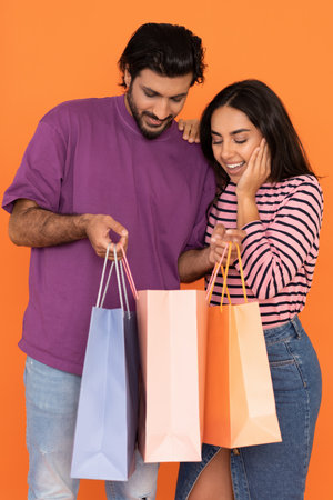 Beautiful young indian couple customers shopping together, checking purchasesの写真素材
