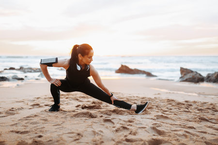 Positive adult european woman in sportswear doing stretching for legs, warming up, enjoy workoutの写真素材