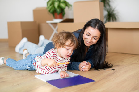 Cute Little Boy And His Mother Relaxing On Floor After Moving Homeの写真素材