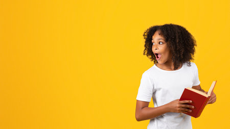 Cheerful shocked surprised teen black curly girl in white t-shirt with open mouth and book looks at...