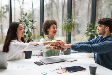 Multiethnic Business Team Celebrating Success Joining Hands In Office Interior