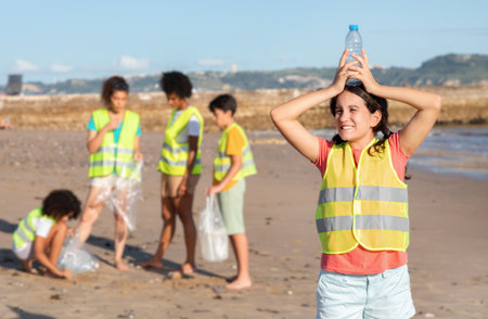 Glad international teenager children in uniform collect garbage and plastic in bag, european girl hold bottleの写真素材