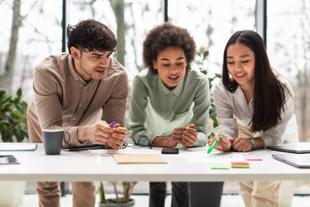 Coworkers Brainstorming Looking At Table With Graphs Talking In Office