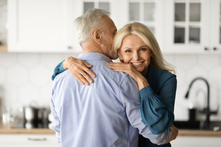 Portrait Of Loving Senior Couple Embracing In Kitchen Interiorの写真素材