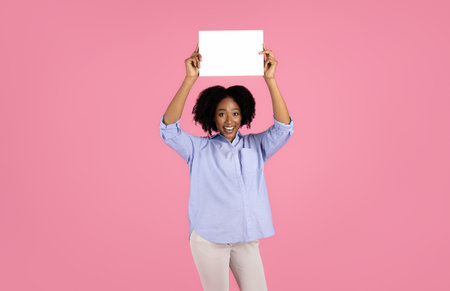 Smiling young pregnant african american curly lady in casual with big belly hold banner with blank spaceの写真素材