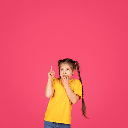 Excited Little Girl Pointing Up With Finger At Copy Spaceの写真素材