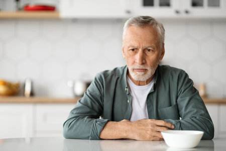 Depression In Seniors. Upset Elderly Man Sitting At Table In Kitchenの写真素材