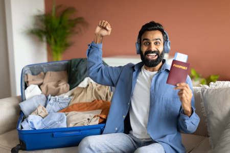 Arabic Traveler Guy Shaking Fists Showing Travel Tickets At Home