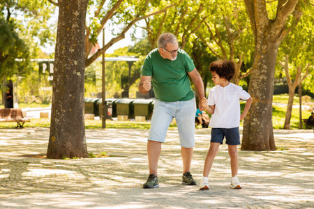 Glad black little boy and man with beard play, rest in park, run competition outdoorの写真素材