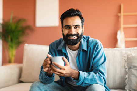 Happy Middle Eastern Man Holding Cup Of Coffee At Homeの写真素材