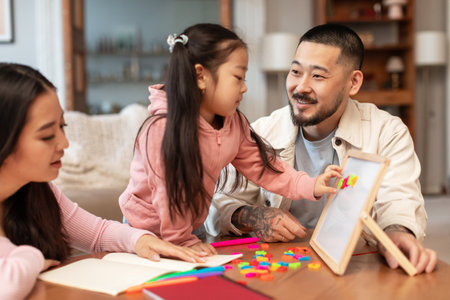 Japanese Parents Teaching Little Daughter Playing Educational Game At Homeの写真素材