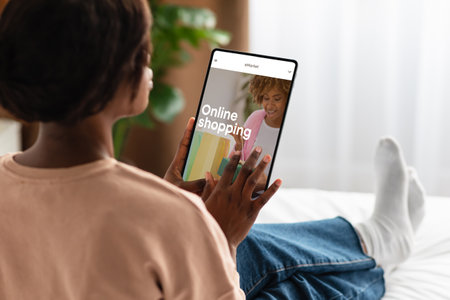 African american lady using tablet with fashion store on screen at home, searching new clothes, enjoy online shoppingの写真素材