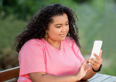 Latin Student Lady Browsing Web On Phone Sitting In Parkの写真素材