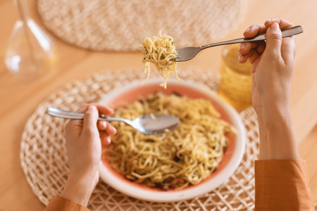 Woman eating Italian pasta with parmesan cheese, spaghetti wind it around a fork with a spoon, pov shotの写真素材