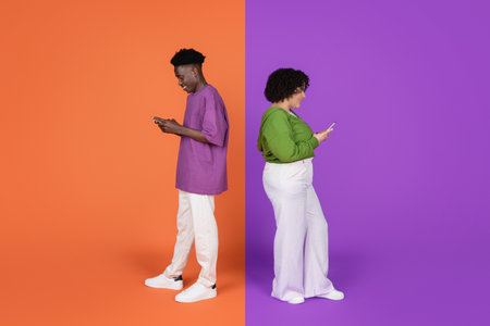 Happy millennial interracial friends using smartphones on color backgrounds