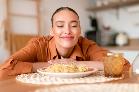 Italian cuisine. Happy satisfied european woman smelling fresh spaghetti on plate, enjoying tasty homemade pastaの写真素材
