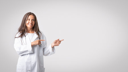 Medical insurance. Friendly caucasian senior woman in medical workwear doctor pointing aside at copy space for adの写真素材