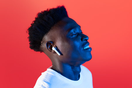 Closeup of thrilled black guy enjoying his newest wireless earphones