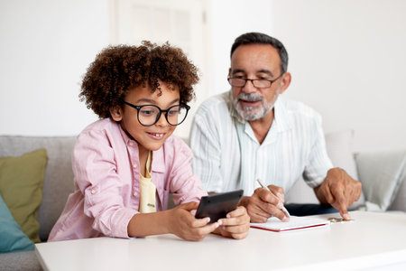 Hispanic Senior Man And Grandson Boy Counting Money At Home