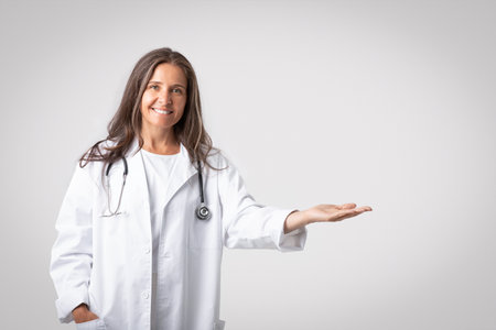 Medical offer concept. Happy senior female physician pointing aside and demonstrating new pill or treatment, mockupの写真素材