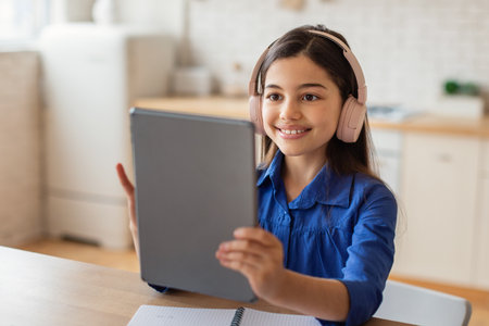 Portrait of happy school girl holding digital tablet at homeの写真素材