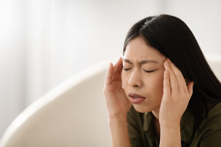 Asian woman in pain touching his head, home interiorの写真素材