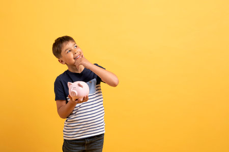 Happy excited school aged boy holding piggy bank, copy spaceの写真素材