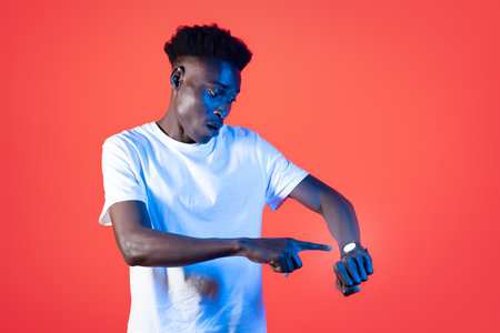 Worried black man checking time on smartwatch on handの写真素材