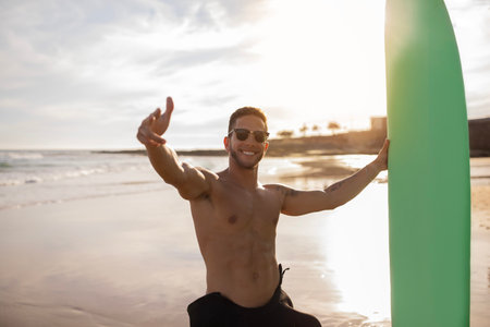 Handsome Young Surfer Guy Holding Surfboard And Pointing Fingers At Cameraの写真素材