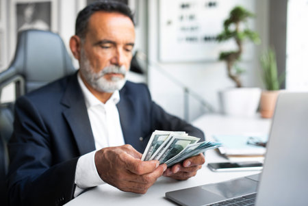 Serious mature european businessman professional in suit works, counts money dollarsの写真素材