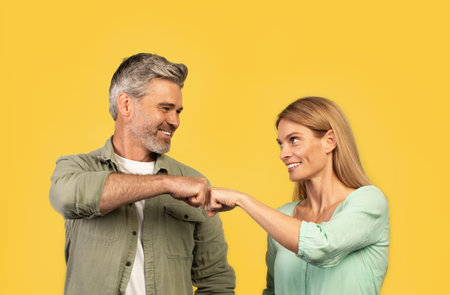 Teamwork concept. Happy middle aged man and woman bumping fists and smiling, celebrating success partnership triumphの写真素材