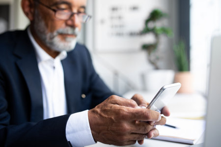 Serious mature european man in suit chatting on phone, use app for check account in office interior, croppedの写真素材