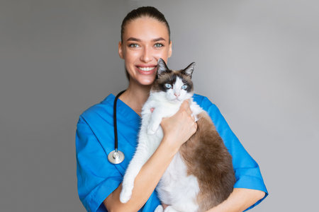 Veterinarian Woman Holding Cute Cat Posing Over Gray Studio Backgroundの写真素材