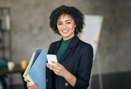 Smiling Black Businesswoman Using Application On Smartphone Standing In Office