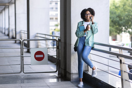 Cheerful millennial black woman standing outside office buildingの写真素材