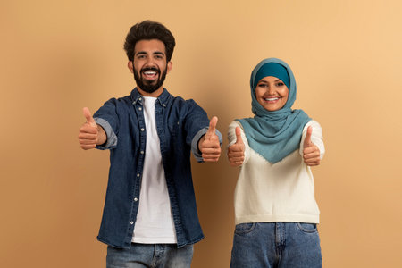 Happy Millennial Muslim Couple Showing Their Thumbs Up At Cameraの写真素材