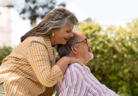 Glad senior european woman doing massage to man, couple enjoy free time together in park, rest and relaxの写真素材
