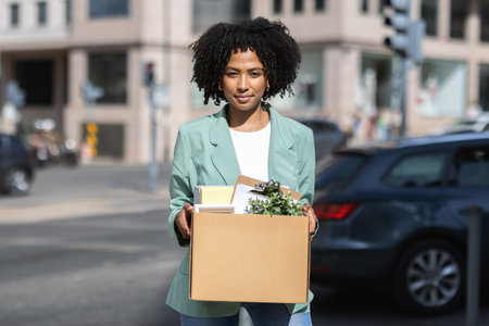 Young attractive black woman in smart casual holding her belongingsの写真素材