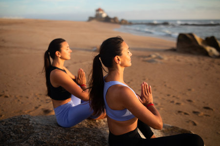 Calm young caucasian women twins with closed eyes in sportswear practice yoga and breathing exercisesの写真素材