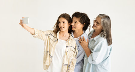 Smiling european old, adult and teenage women make photo on smartphoneの写真素材
