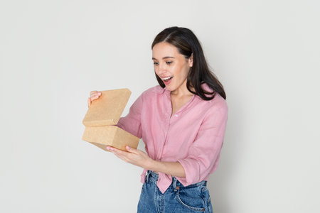 Emotional pretty millennial lady opening cardboard box