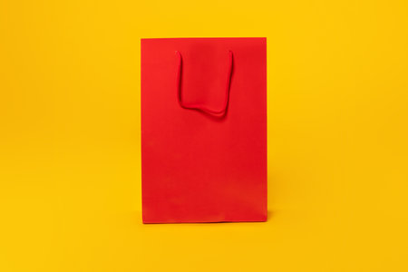 Season sales. Huge empty red shopping bag on yellow studio background, mockup, free space, place for your text or designの写真素材