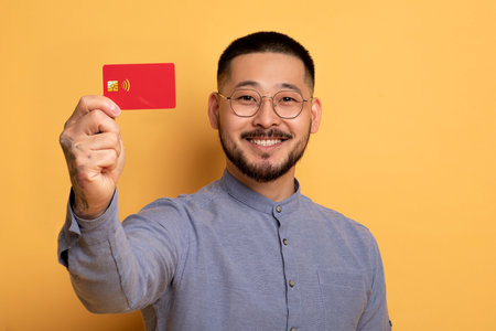 Smiling Young Asian Guy Showing Credit Card At Cameraの写真素材