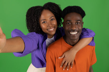 Glad young african american woman hug man, have fun, make selfie, enjoy free timeの写真素材