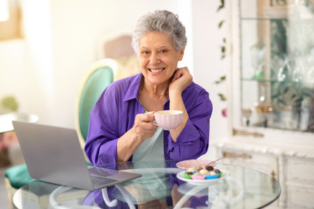 Happy Senior Lady Using Laptop And Having Coffee In Cafe